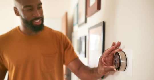man adjusting smart thermostat