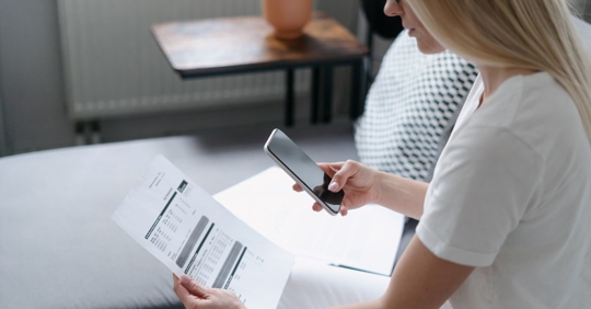 woman looking at utility bill that increases from inefficient HVAC systems